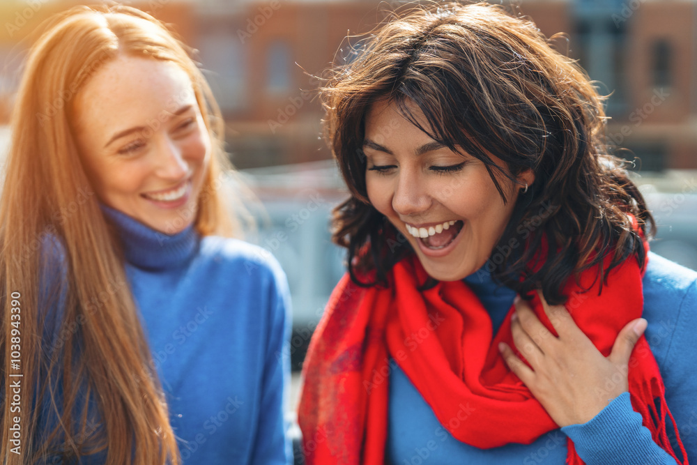 Obraz premium Joyful friendship between two women with bright scarves enjoying their day in a bustling city at sunset