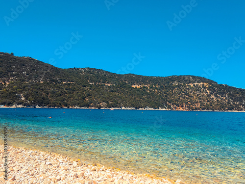 Serene beach with pebbles and turquoise water under a clear blue sky.