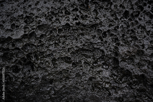 Black grey background lava stone with erosion holes caused by wind, water and weather. Backdrop surface weathered grunge and furrowed.