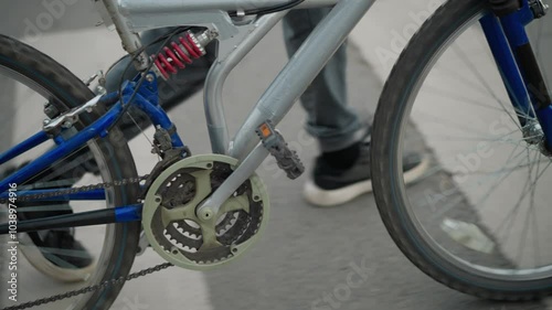 Wallpaper Mural Close-up of bicycle chain and pedal as a person in grey pants, black sneakers walks alongside it across a pedestrian crossing painted with white color Torontodigital.ca