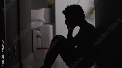 Depressed young man sitting on floor. Portrait of anxious handsome man on the floor having business or personal problems feeling stressed and desperate
 photo