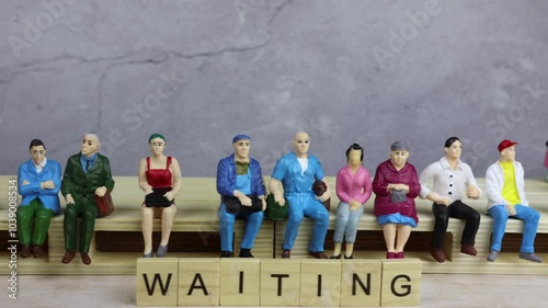 A group of people doll miniatures sitting on a palette, waiting in front of a concrete wall. Waiting for luck love train station Better future Life opportunities procrastinating