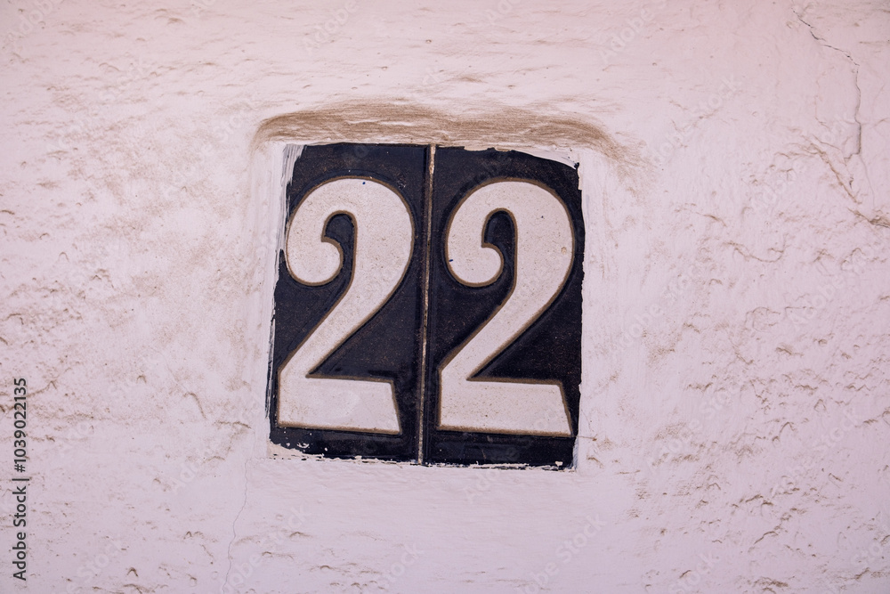 Beautiful house number 22 in Spanish style. House number on a ceramic patterned base in the old town in Spain. Traditional Spanish patterned decoration of a plate with an apartment or house number Beautiful house number 22 in Spanish style. House number on a ceramic patterned base in the old town in Spain. Traditional Spanish patterned decoration of a plate with an apartment or house number