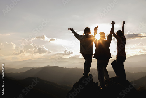 Fototapeta Naklejka Na Ścianę i Meble -  Silhouette group of people holding hands raise their hands to sunset sky on top mountain,