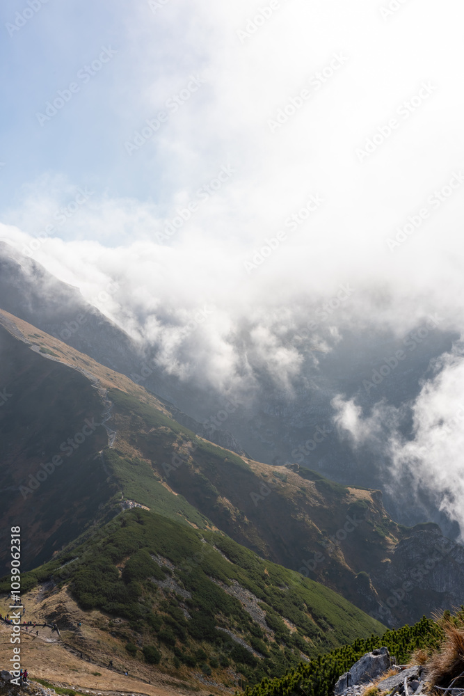 Majestic mountain ridge covered in mist, with a winding trail cutting through the rugged landscape. Spirit of adventure, connection with nature, allure of remote high-altitude destinations. Majestic mountain ridge covered in mist, with a winding trail cutting through the rugged landscape. Spirit of adventure, connection with nature, allure of remote high-altitude destinations.
