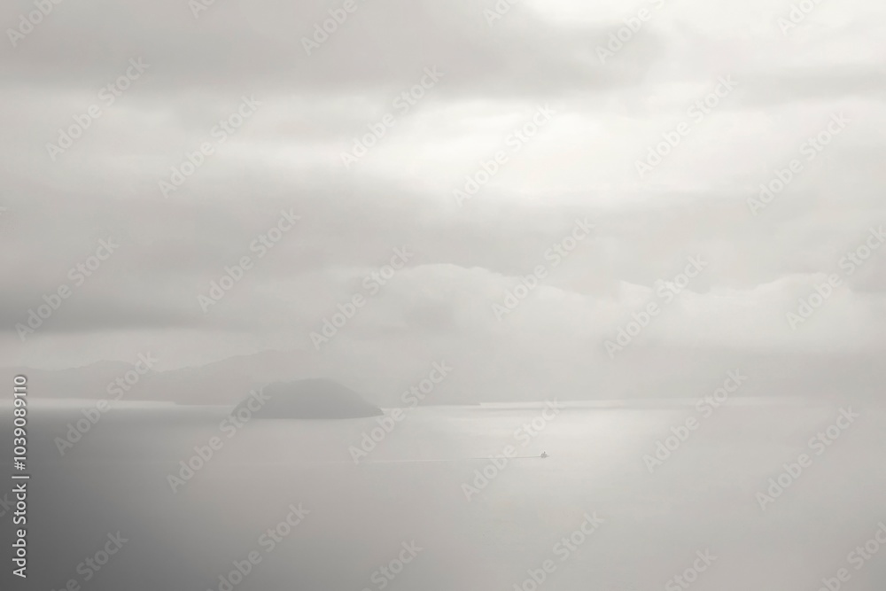 Obraz premium A Small Boat Navigates a Foggy Sea with a Single Island in the Distance