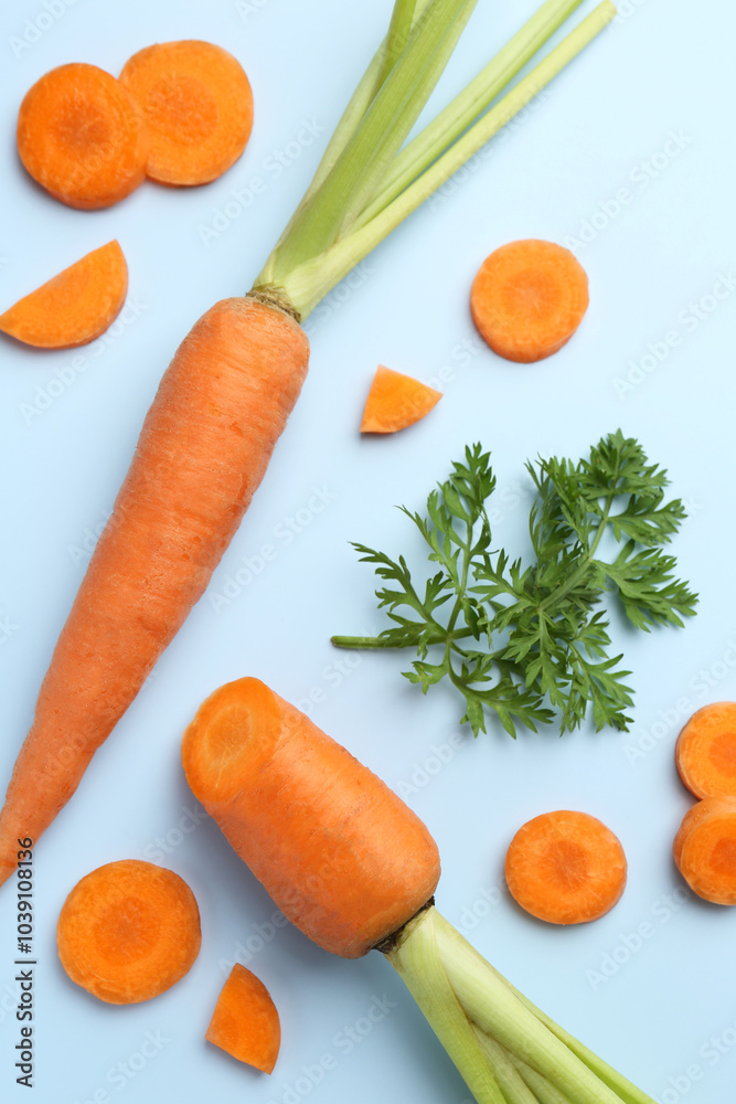 Whole and cut fresh carrots with green leaf on light background, flat lay Whole and cut fresh carrots with green leaf on light background, flat lay