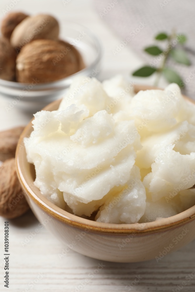 Shea butter in bowl and nuts on white wooden table, closeup Shea butter in bowl and nuts on white wooden table, closeup
