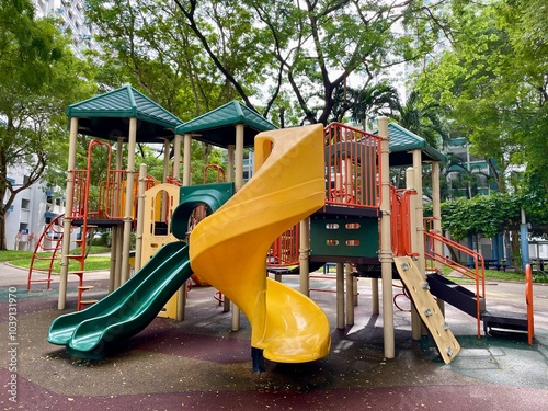 children's playground with a variety of play structures. The playground is surrounded by grass and trees