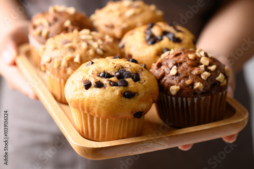 Vanilla chocolate chips muffin, Chocolate almond muffin and Vanilla almond muffin on wooden plate holding by hand