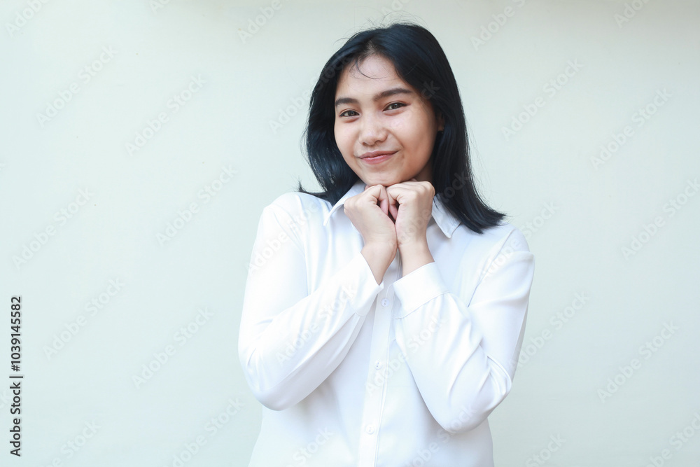 image of cute pleased asian woman manager wearing white suit shirt smile at camera with fist pump on chin showing satisfied expression standing over isolated background image of cute pleased asian woman manager wearing white suit shirt smile at camera with fist pump on chin showing satisfied expression standing over isolated background