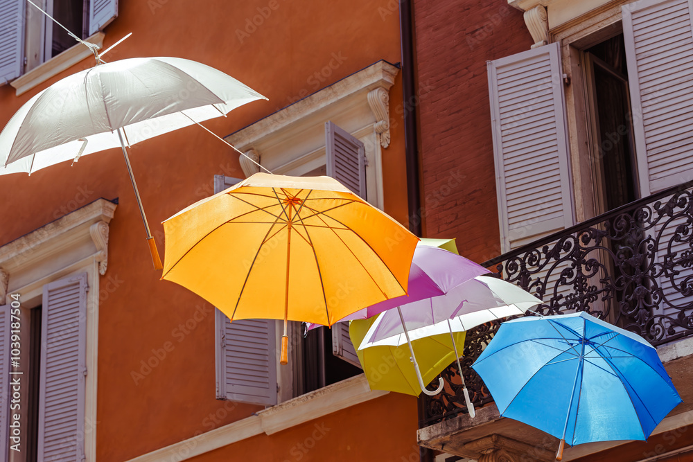 Colorful umbrellas create a vibrant canopy over a charming street in a scenic town of the Modena, Italy,