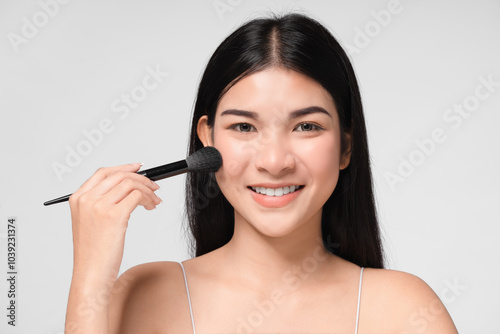 Beautiful Asian young woman smile and holding make up brush with healthy Clean and Fresh skin isolated on white background. Beauty Cosmetics Concept.