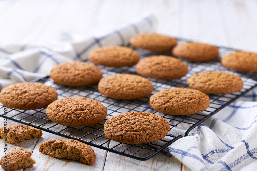 Freshly baked oatmeal cookies cooling on a black wire rack, with in a light kitchen table, selective focus. Freshly baked oatmeal cookies cooling on a black wire rack, with in a light kitchen table, selective focus.