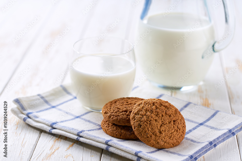 Low-calories oatmeal cookies and a jug of fresh milk on a light kitchen table,healthy breakfast. Low-calories oatmeal cookies and a jug of fresh milk on a light kitchen table,healthy breakfast.