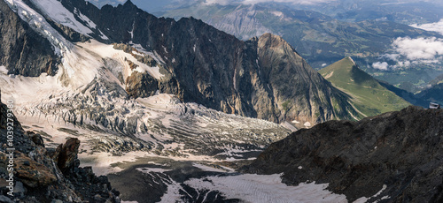 Dirty melted end of glacier under Mont Blanc between high rock walls and clouds