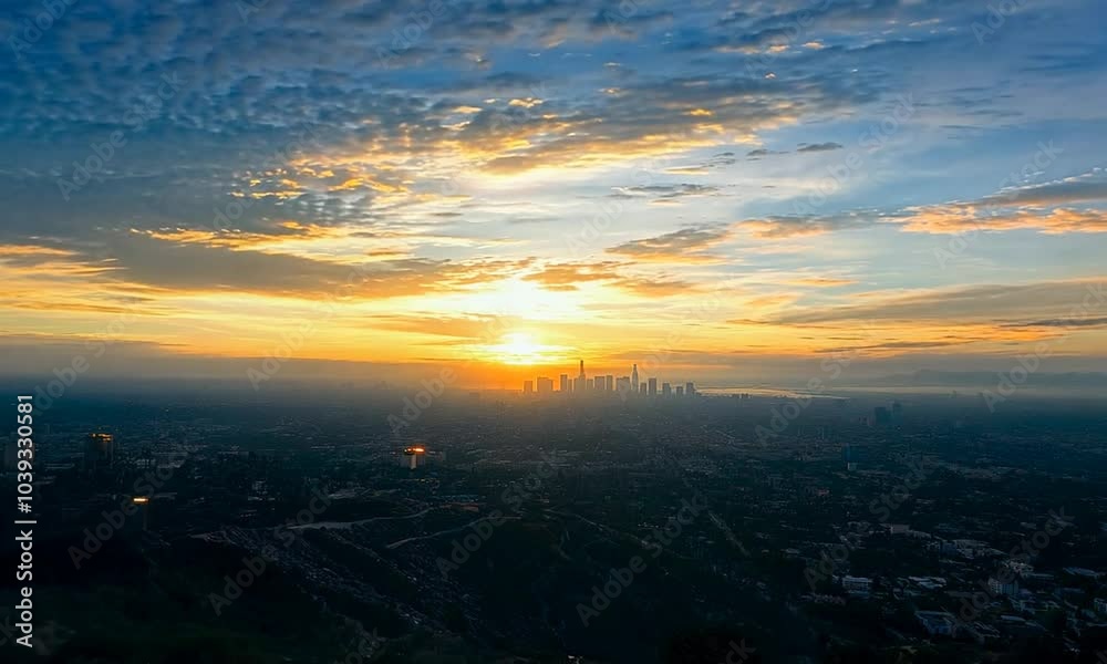 A fiery sunrise casts a golden glow over a city skyline, with clouds in the sky.