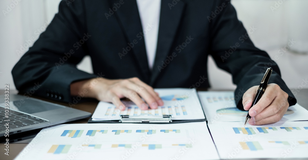 The businessman hand sits at their desks and calculates financial graphs showing the results of their investments planning the process of successful business growth The businessman hand sits at their desks and calculates financial graphs showing the results of their investments planning the process of successful business growth