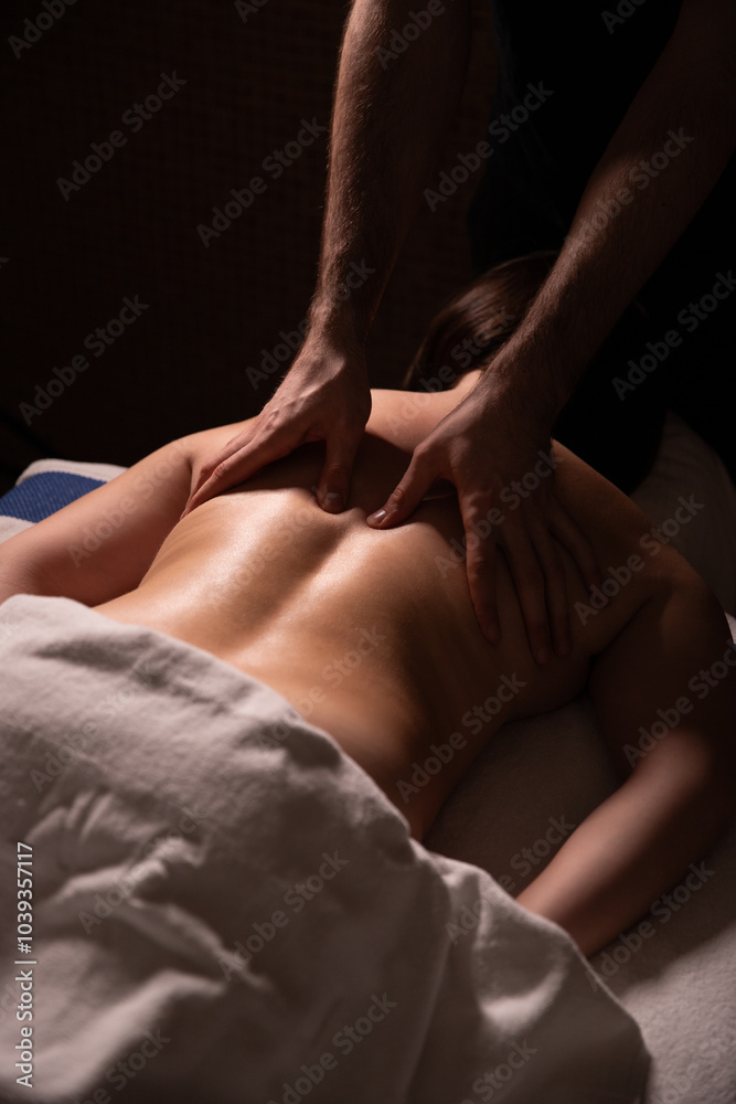 A relaxing back massage performed by a woman's hands, emphasizing comfort and wellness. Ideal for themes of spa treatments, body care, and therapeutic massage in the dark A relaxing back massage performed by a woman's hands, emphasizing comfort and wellness. Ideal for themes of spa treatments, body care, and therapeutic massage in the dark