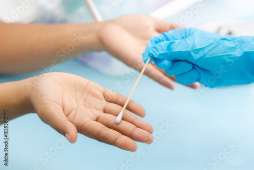 Scientist's hand holding a cotton swab and wiping dipped in diluted rubbing alcohol to hands and fingers. Cleaning dirty fingers to test for disease for food safety is a process of measuring in lab. photo