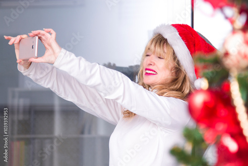 Mature woman taking selfie or live video on mobile phone at Christmas photo