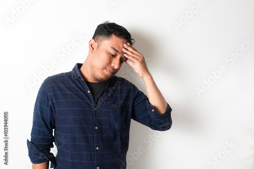 Adult Asian man with head down showing stress expression photo