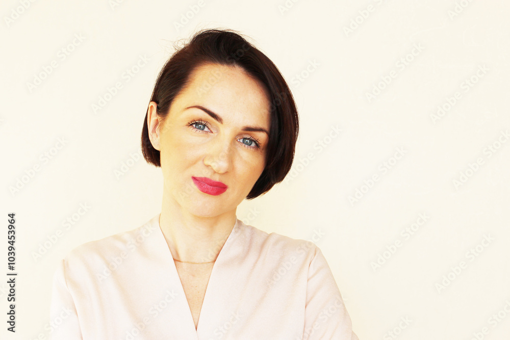 brunette girl with short hair in a stylish bob and red lips. the look is filled with confidence, a smile and cheerfulness. Beige light background, beige or white blouse, modern feminine style. brunette girl with short hair in a stylish bob and red lips. the look is filled with confidence, a smile and cheerfulness. Beige light background, beige or white blouse, modern feminine style.