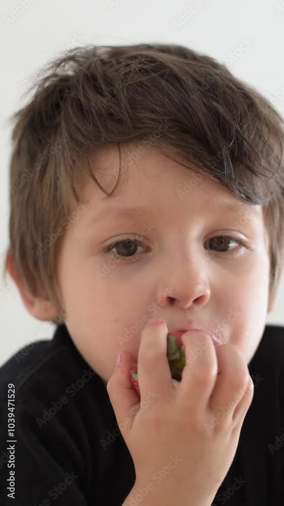 niño latino comiendo fresas, primer plano de su rostro niño latino comiendo fresas, primer plano de su rostro