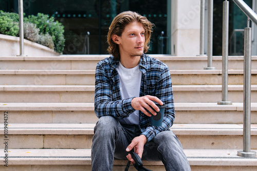 Young man with long hair sitting on steps photo