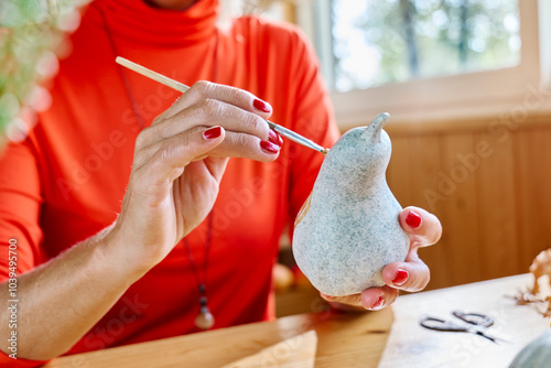 Woman painting artificial gourd at home photo