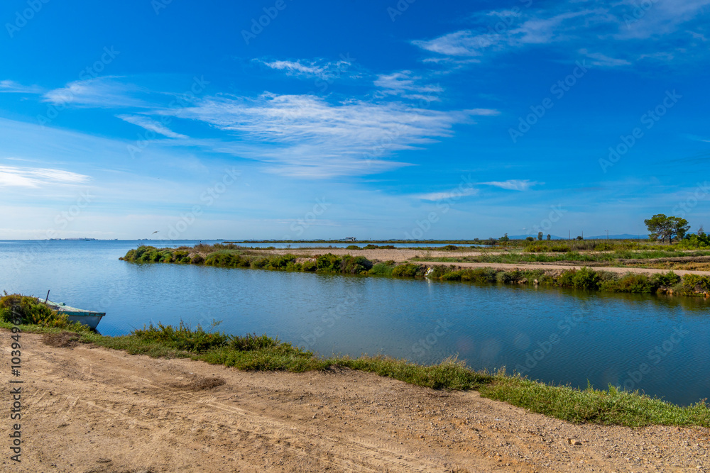 Natural landscape of the mouth of the Ebro Delta with the calm waters and the coast in the background and the vision of the visual effect of Fata Morgana with a camper van in the background. Natural landscape of the mouth of the Ebro Delta with the calm waters and the coast in the background and the vision of the visual effect of Fata Morgana with a camper van in the background.