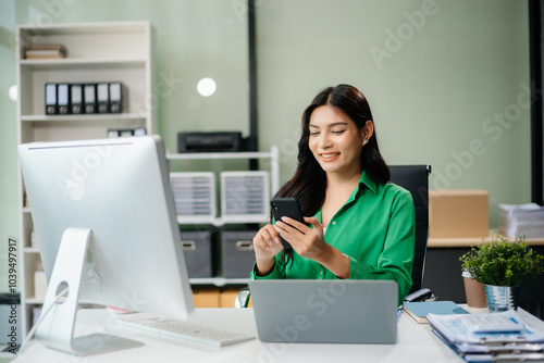 Asian woman using laptop and tablet while sitting at her working place. Concentrated