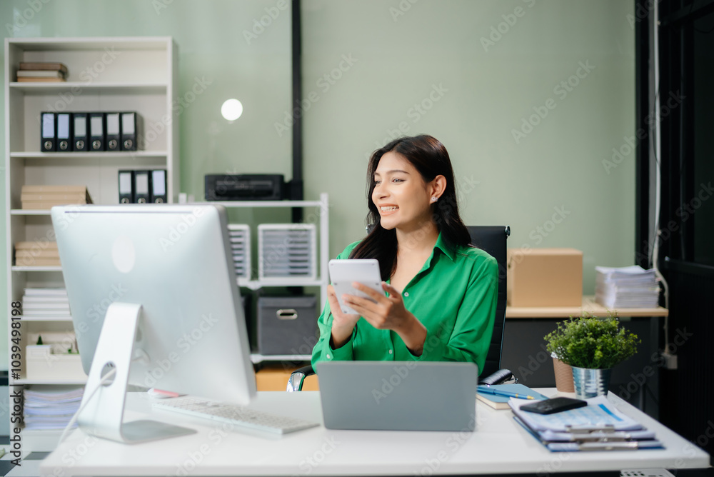 Asian woman using laptop and tablet while sitting at her working place. Concentrated Asian woman using laptop and tablet while sitting at her working place. Concentrated