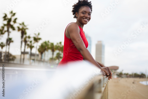 Smiling woman with short hair near railing at beach photo