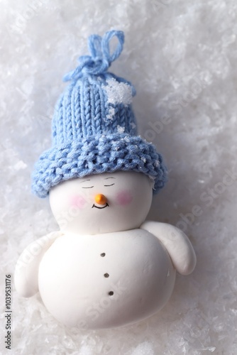 Cute decorative snowman on artificial snow, top view