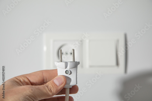 Hand holding electric plug into a power outlet. photo