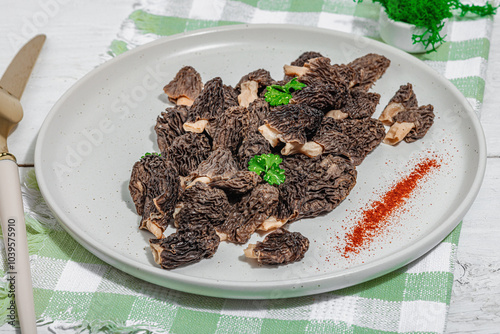 Raw black morel mushrooms with fresh parsley. Vegan ingredient for cooking healthy food photo