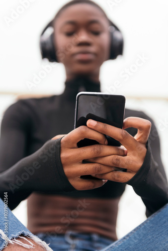 Canvas Print low angle of unrecognizable young glad ethnic female in wireless headphones surf