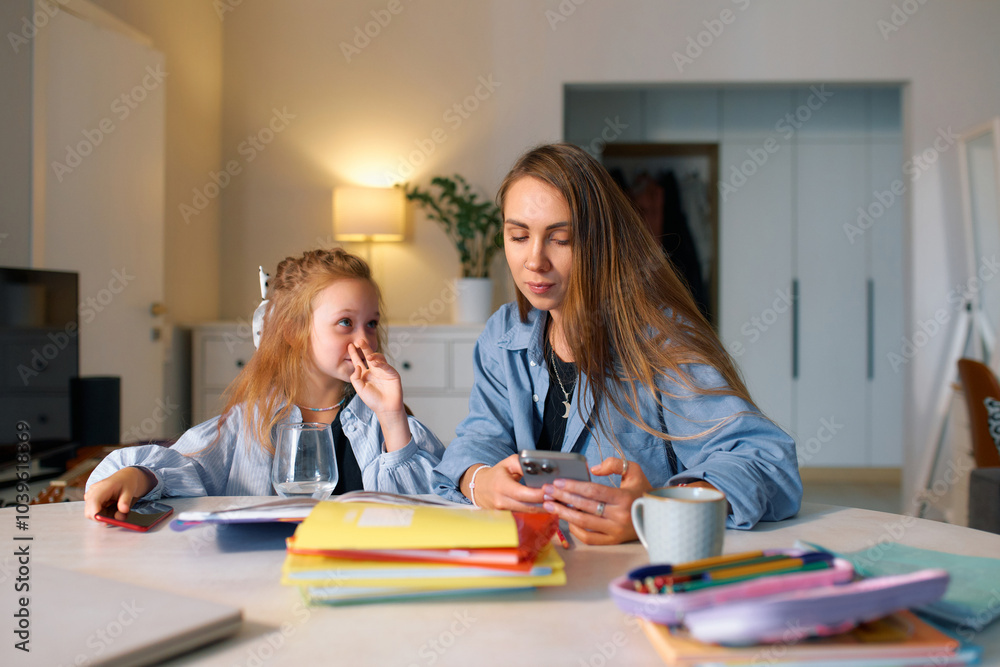 Fototapeta premium A schoolgirl sits at home with her mother and does her homework