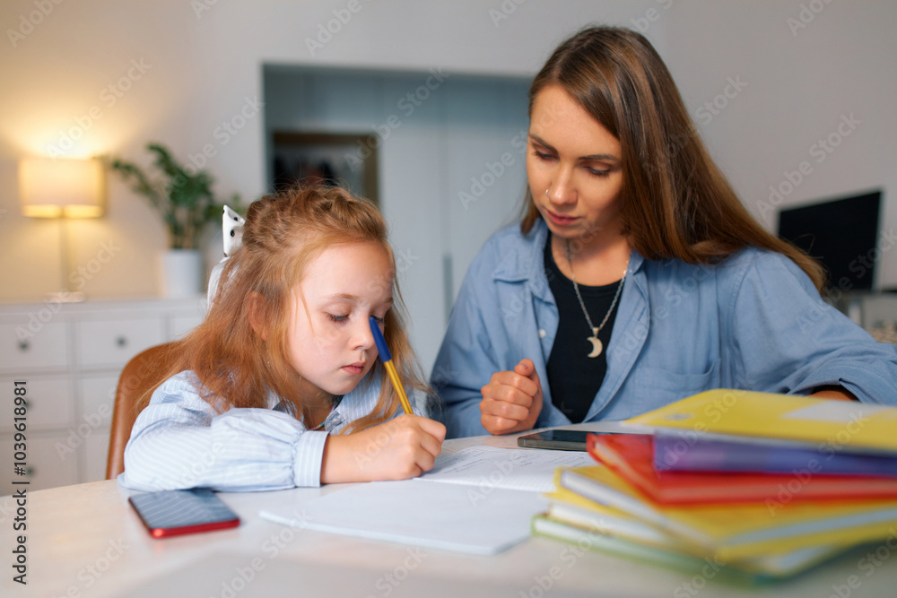 Red-haired schoolgirl with her mother learns the school curriculum remotely Red-haired schoolgirl with her mother learns the school curriculum remotely