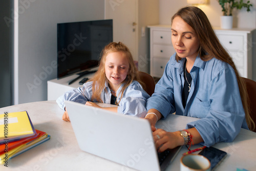 Young schoolgirl and her mother doing homework for a school lesson