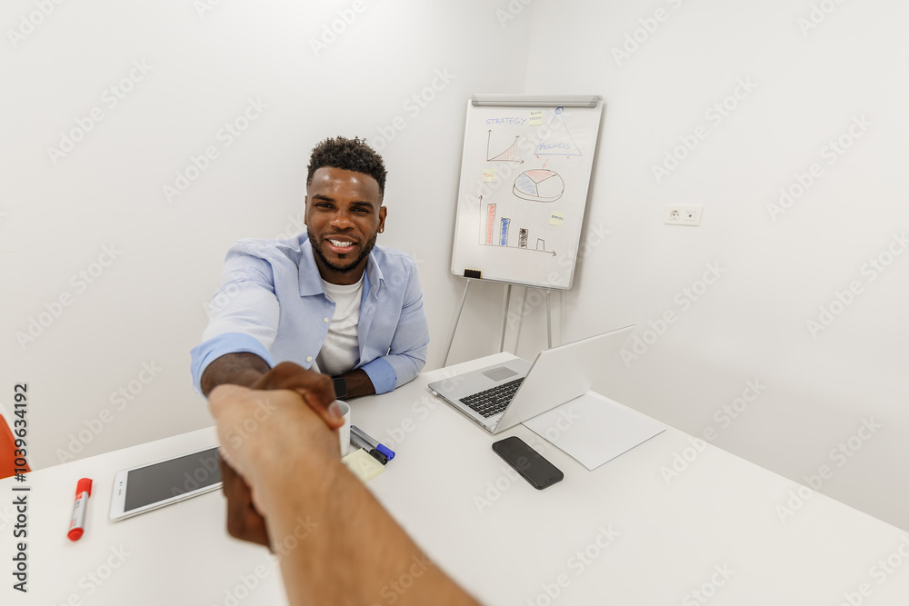 Two professionals shake hands at a clean white office table, showing teamwork. Two professionals shake hands at a clean white office table, showing teamwork.