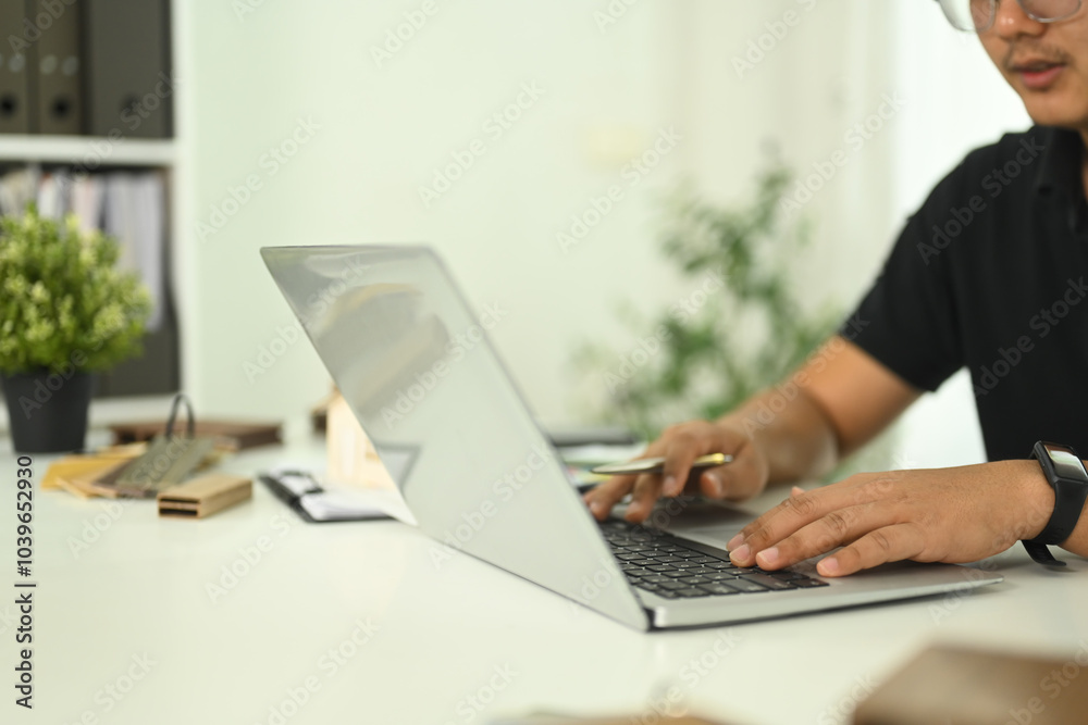 An architect or design professional typing on laptop working on a design project in a modern office An architect or design professional typing on laptop working on a design project in a modern office