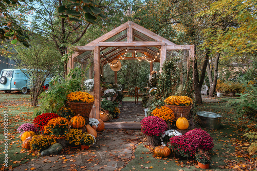 Fototapeta Naklejka Na Ścianę i Meble -  Charming gazebo with autumn flowers and pumpkins in a cozy garden