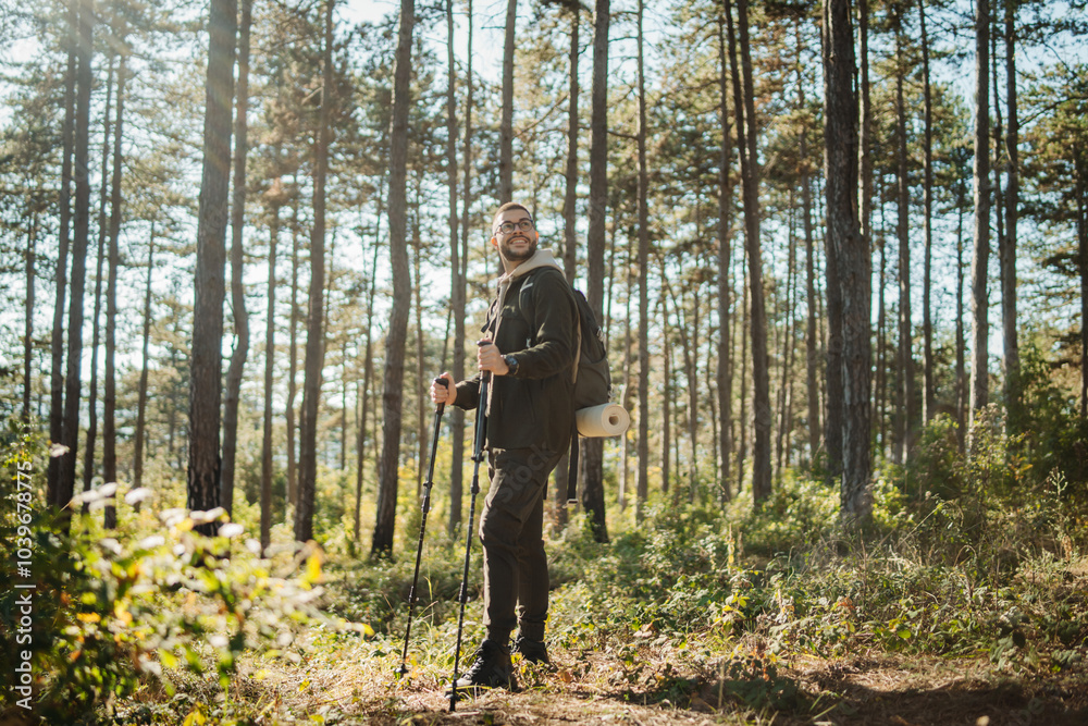 Young caucasian man hiking or trekking through the forest Young caucasian man hiking or trekking through the forest