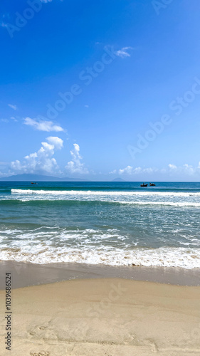 A tranquil beach scene under a clear blue sky, perfect for summer vacations and relaxation, with small boats on the horizon