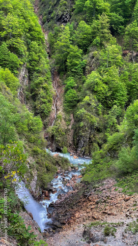 A picturesque mountain stream cascades through lush green forest, ideal for promoting eco-tourism and nature conservation awareness