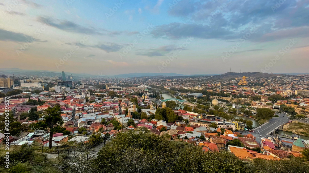 Obraz premium A panoramic view of Tbilisi, Georgia, showcases historic architecture and the Kura River, perfect for travel and urban exploration themes