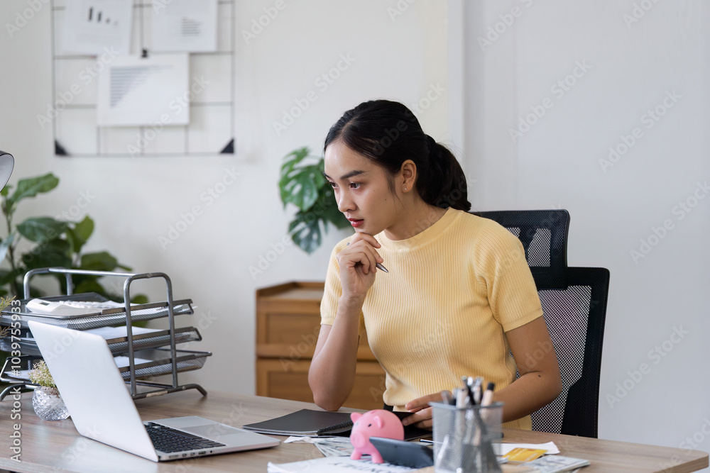 Young Woman Engaged in Financial Planning and Money Management at Home Office with Laptop and Documents Young Woman Engaged in Financial Planning and Money Management at Home Office with Laptop and Documents