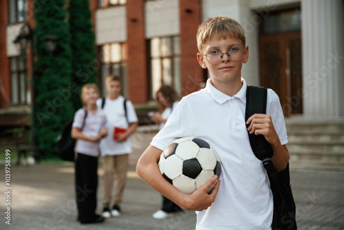 Boy is with soccer ball. Kids are near the school together, pupils photo